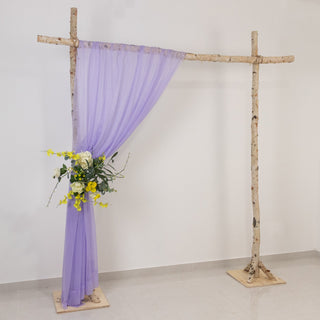 Wooden wedding arch with lavender draping and floral arrangement.