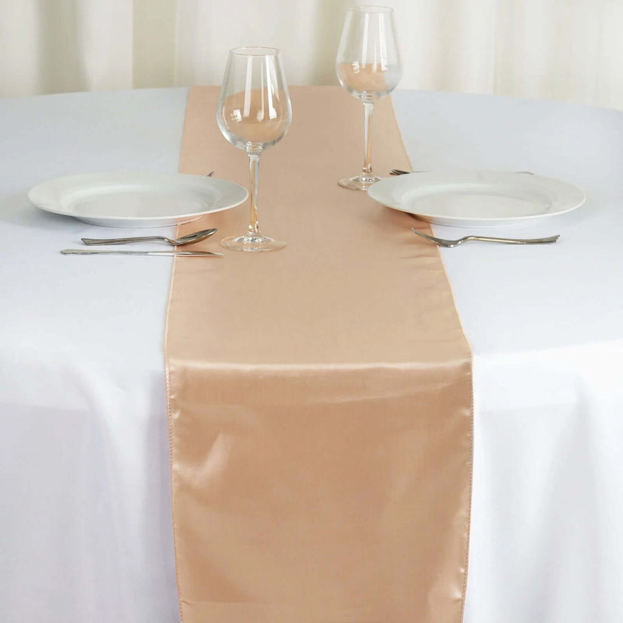 Elegant peach satin table runner on a white table setting with glassware and plates. #whtbkgd