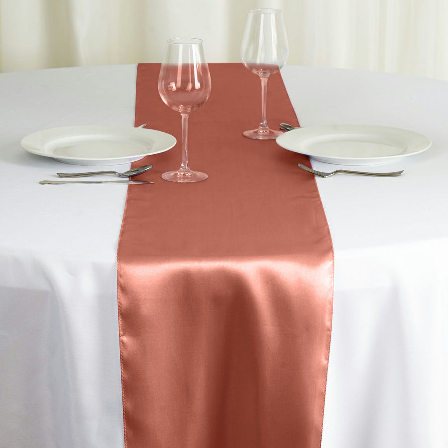 Elegant rose satin table runner on a white table setting with glassware.