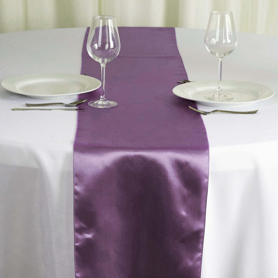 Purple satin table runner on a white table with plates and glasses. #whtbkgd