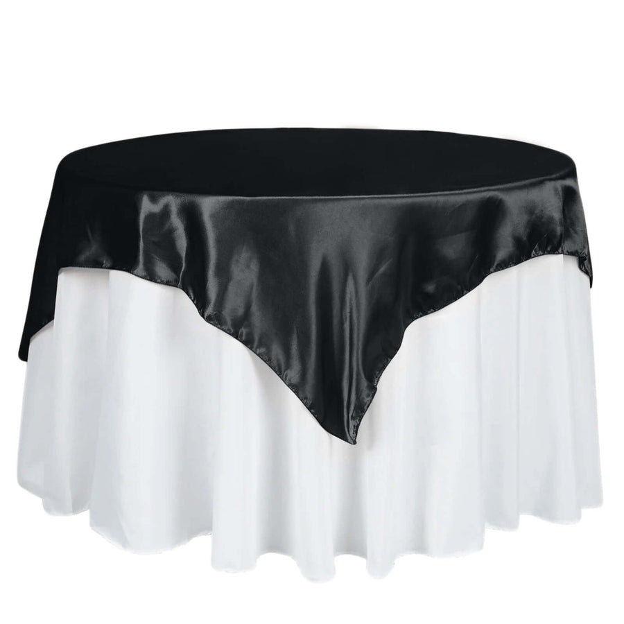 Black satin tablecloth draped over a round table with white underlayer