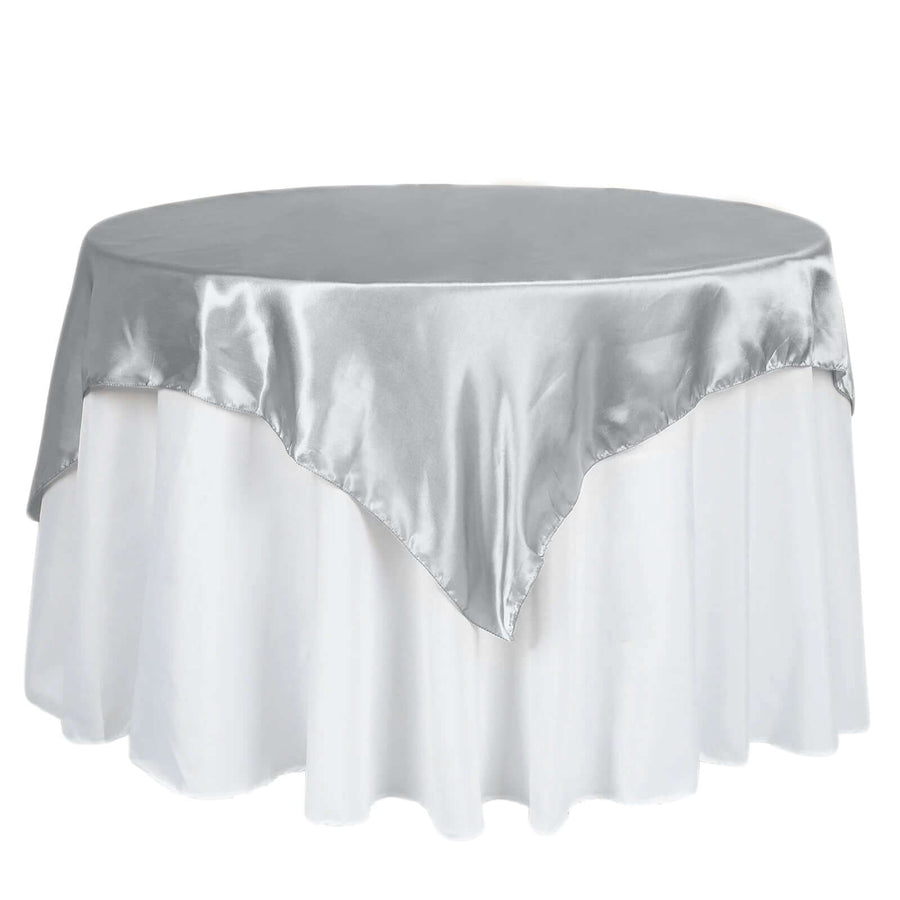 Silver satin tablecloth on a round table with a white skirt.