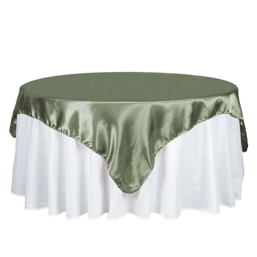 Green satin tablecloth draped over a round table with a white skirt.
