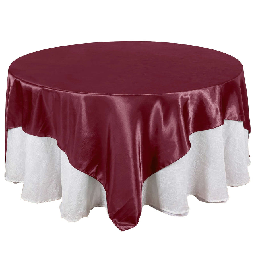 Burgundy round tablecloth with white lace trim on a plain background