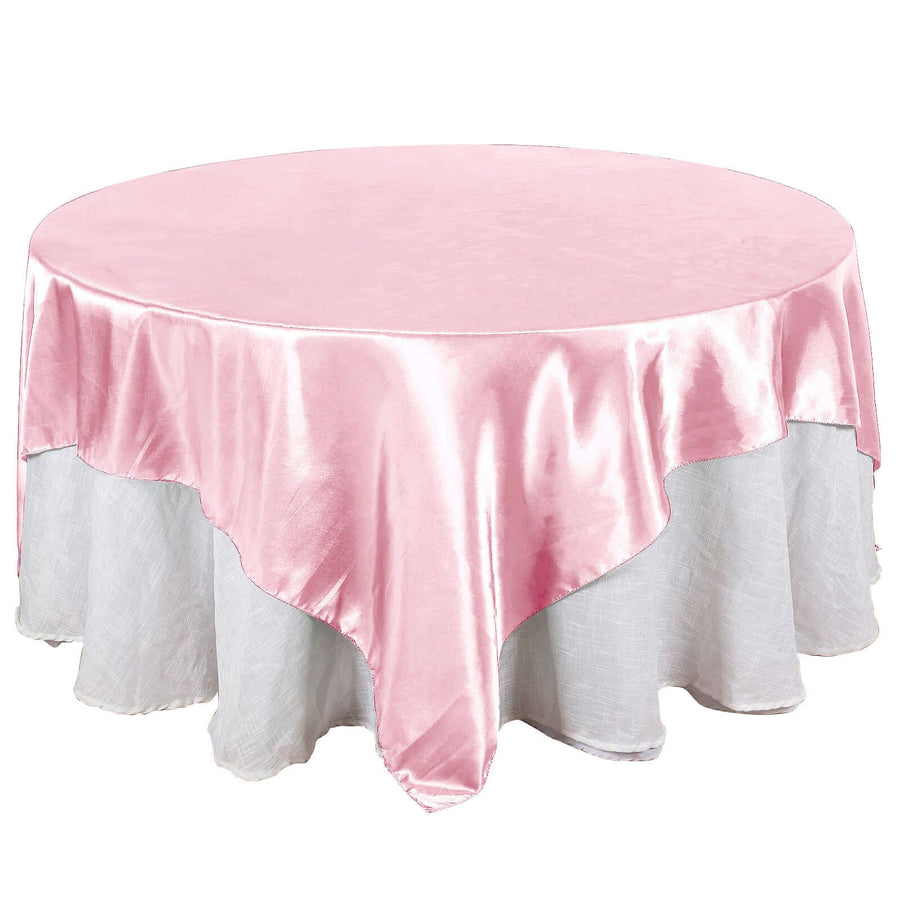 Round pink satin tablecloth with white underlayer on a plain backdrop