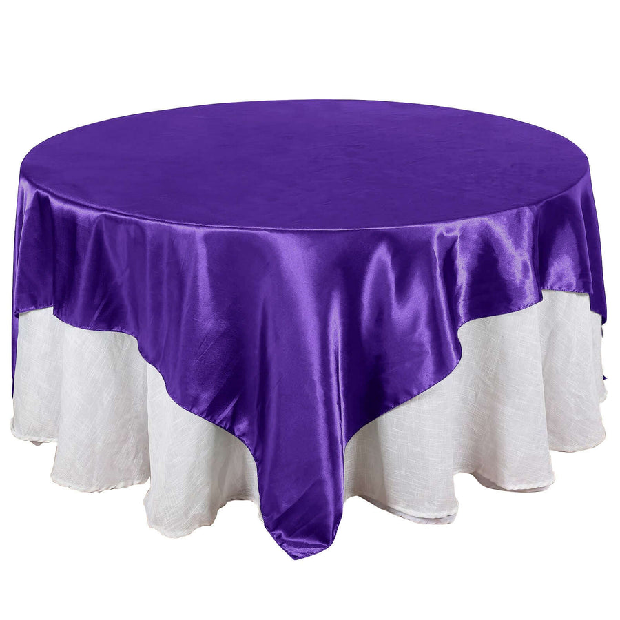 Purple round tablecloth with white underlay, elegantly draped.