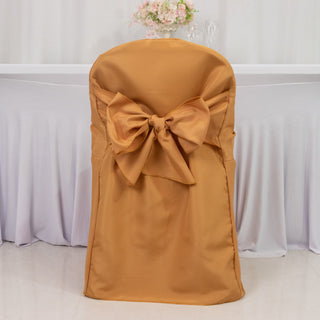 Elegant gold chair cover with large bow for event decoration.