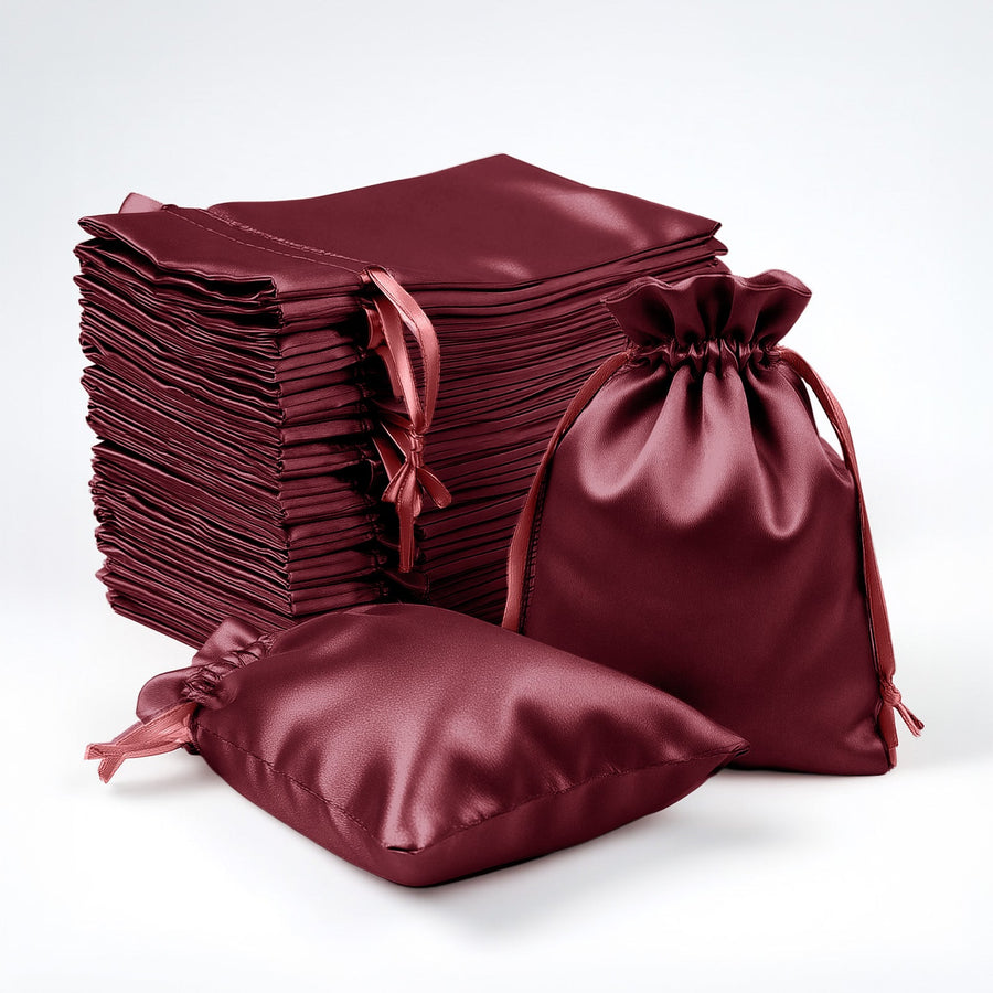 Burgundy satin drawstring bags and fabric squares stacked on a white background