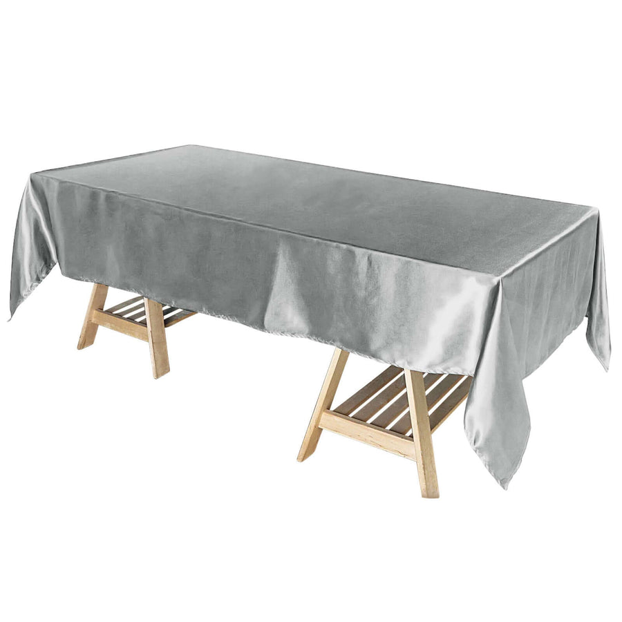 Silver satin tablecloth draped over a wooden table.
