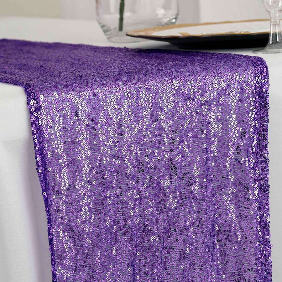 Purple sequin table runner on a white tablecloth.