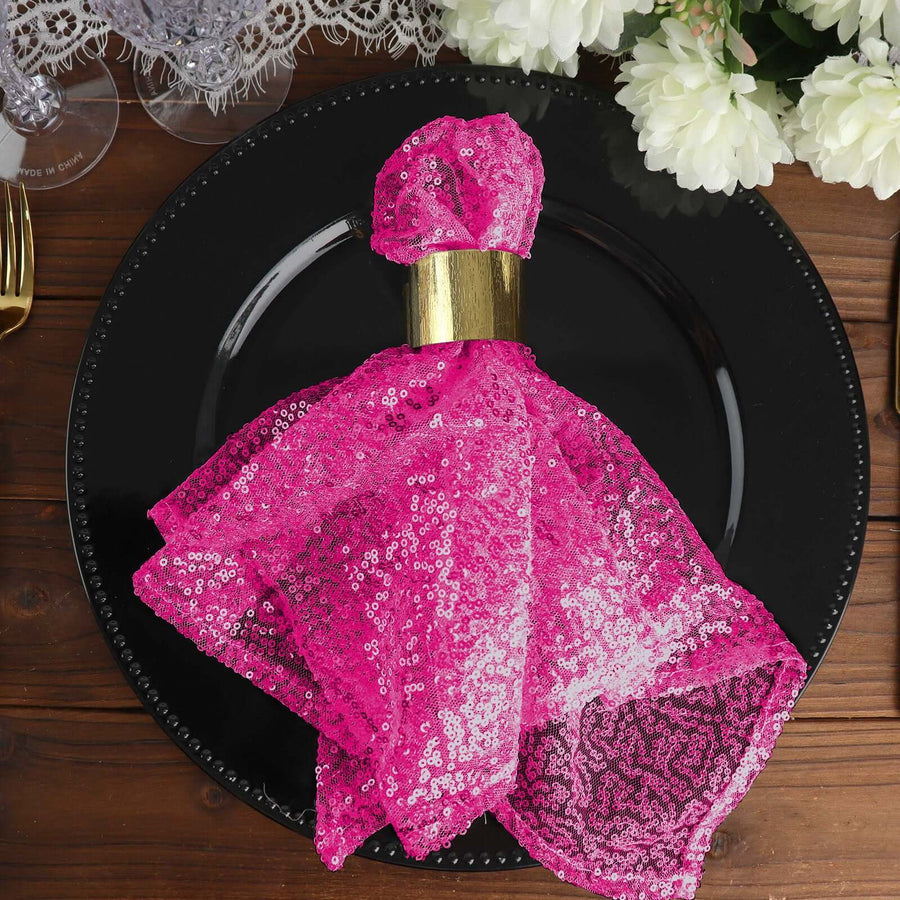 Pink sequin napkin on a black plate, elegantly styled for a dining setting.
