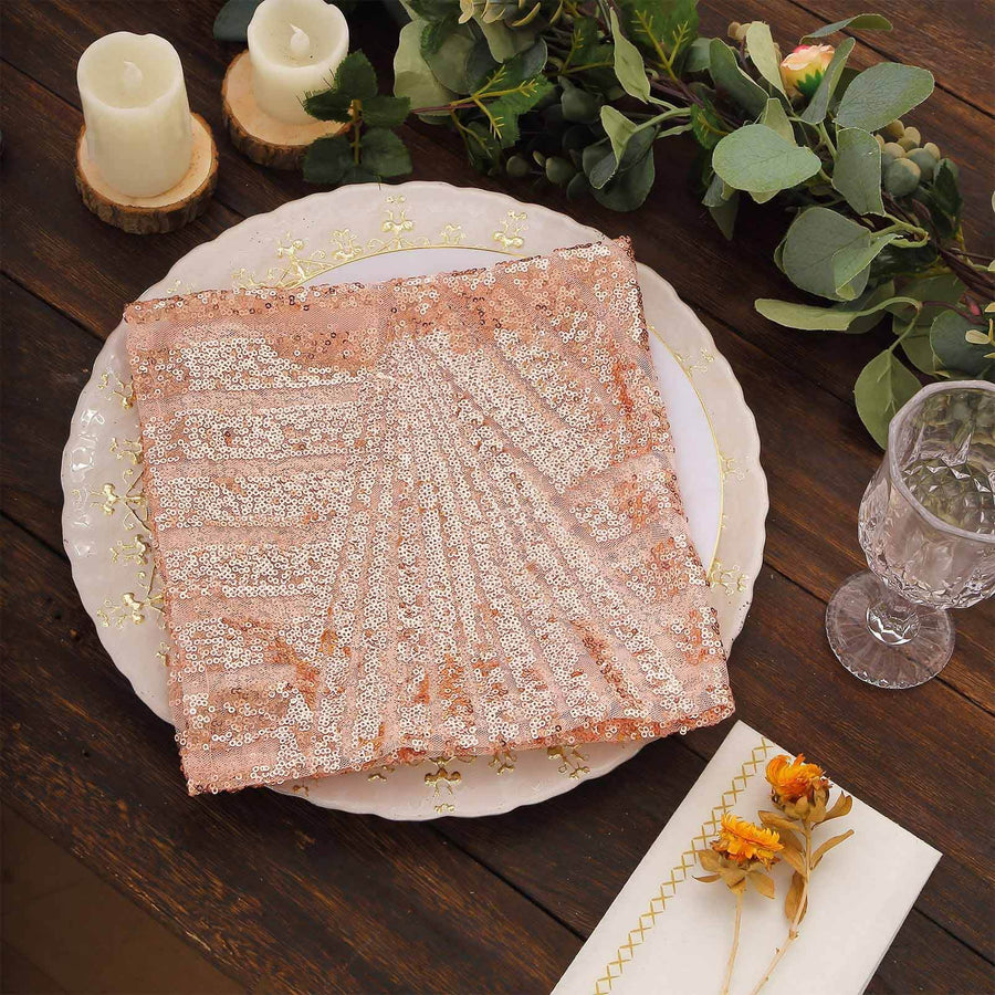Rose gold sequined table runner on a decorative plate with candles and greenery.