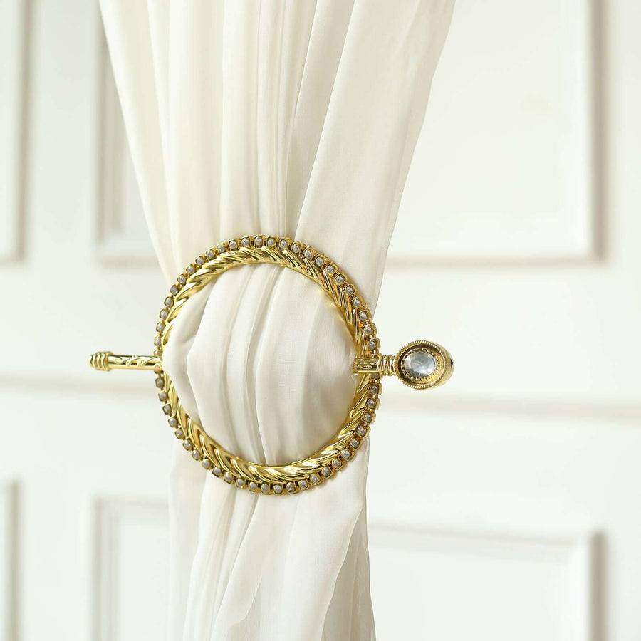 Gold curtain tieback with decorative detailing on a soft white curtain.