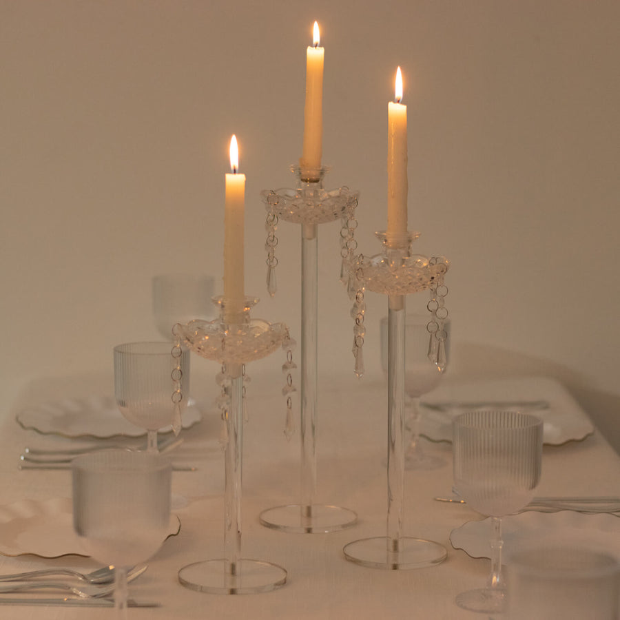 Elegant glass candle holders with lit candles on a dining table.