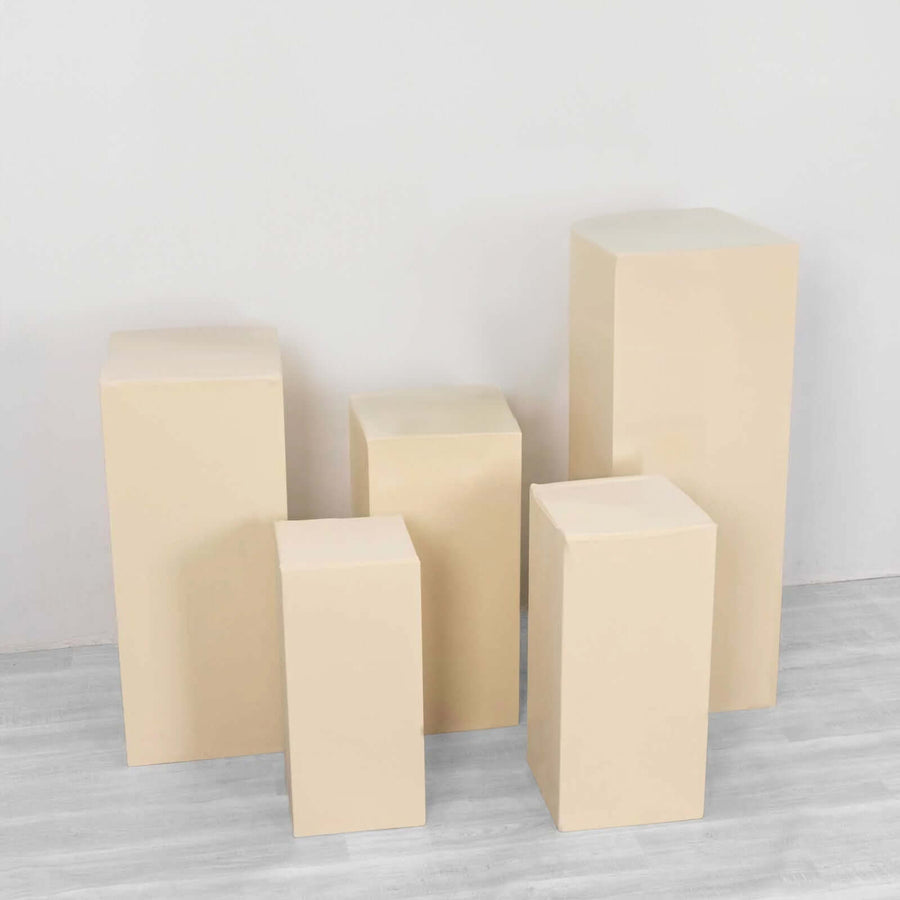 Beige display pedestals in various heights on a plain background.