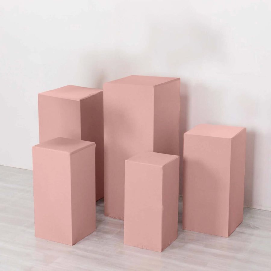 Pink display pedestals in various heights against a plain backdrop.