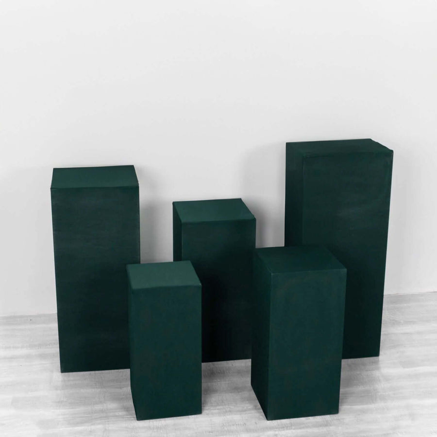Green display pedestals in various heights on a plain backdrop