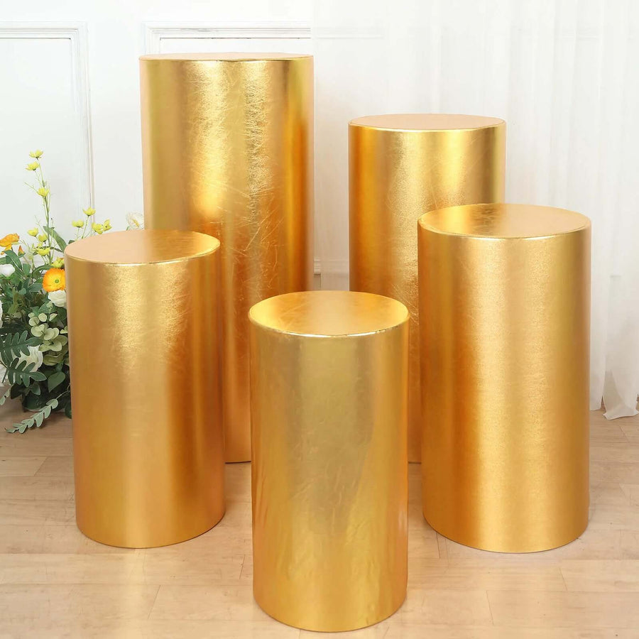 Set of five gold display pedestals in varying heights, ideal for events or decorations.