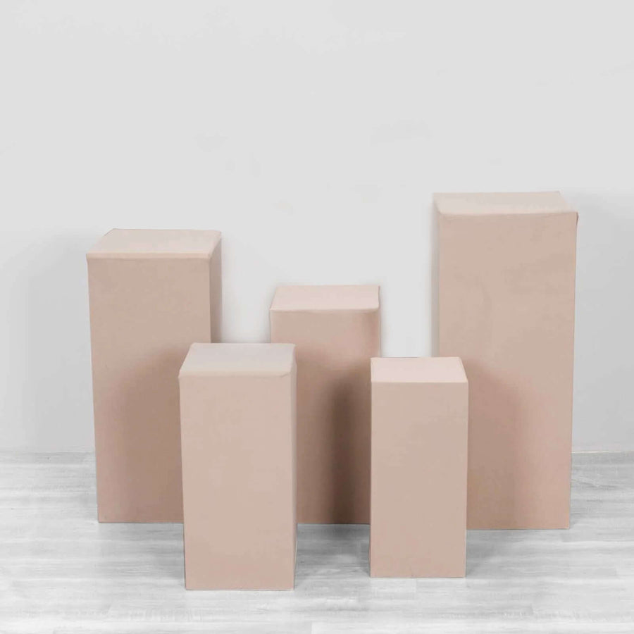 Set of five beige display pedestals on white background