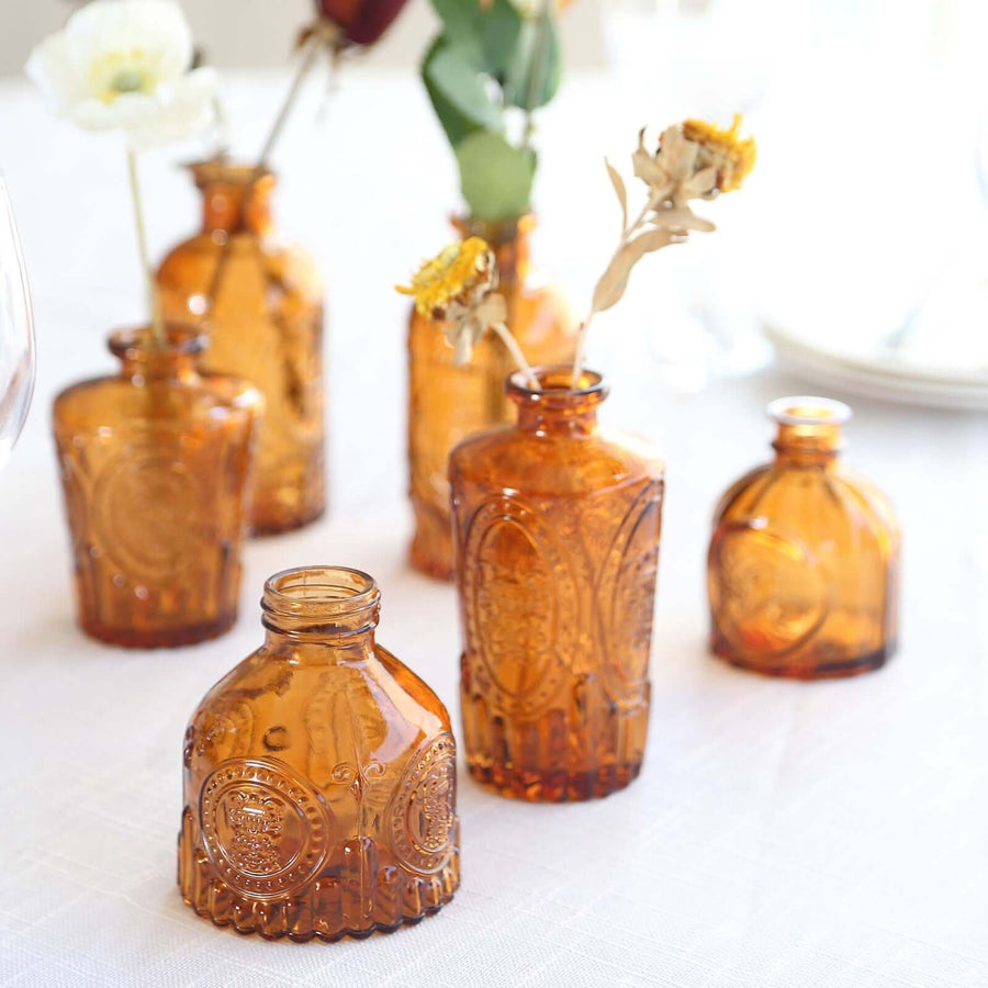 Amber glass vases with dried flowers arranged on a table