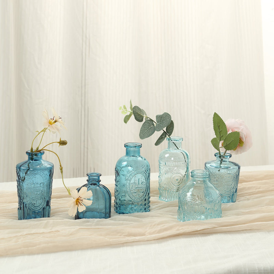 Assorted blue decorative vases with flowers on a table.