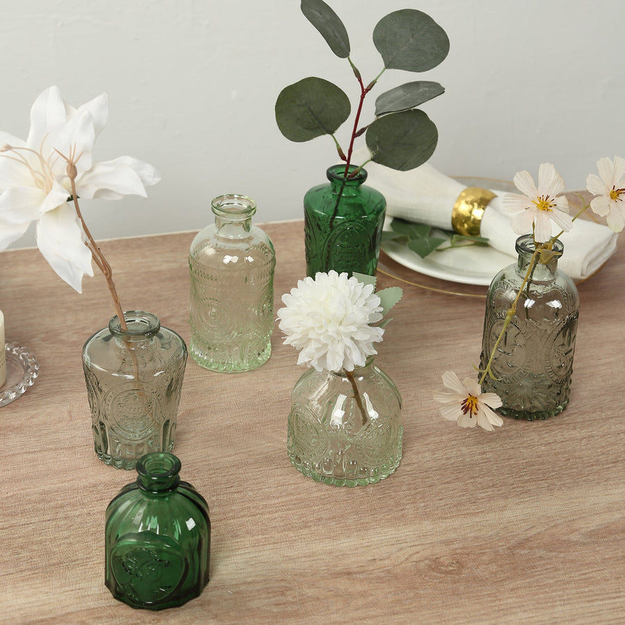 Assorted decorative glass vases with flowers on a wooden table.