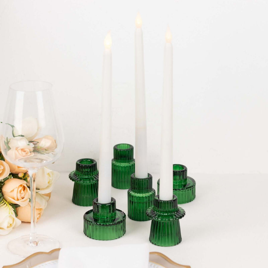 Green glass candlestick holders with white candles and a glass of wine