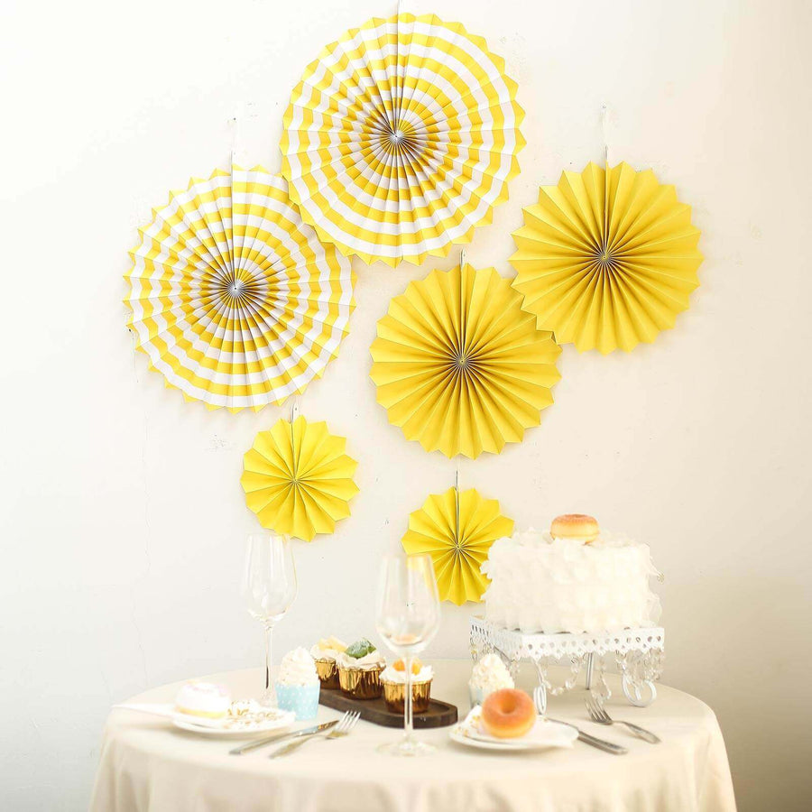 Yellow paper decorations on a wall above a dessert table with cake and pastries.