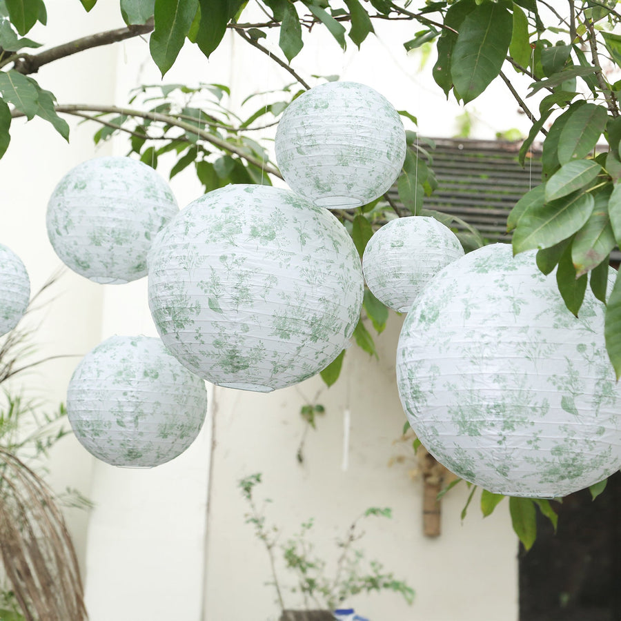 Green floral paper lanterns hanging from branches outdoors.