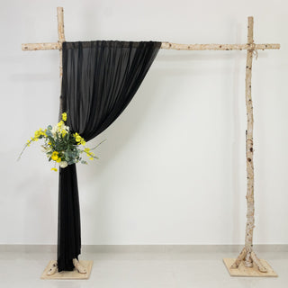 Black drapery on rustic wooden frame with floral arrangement