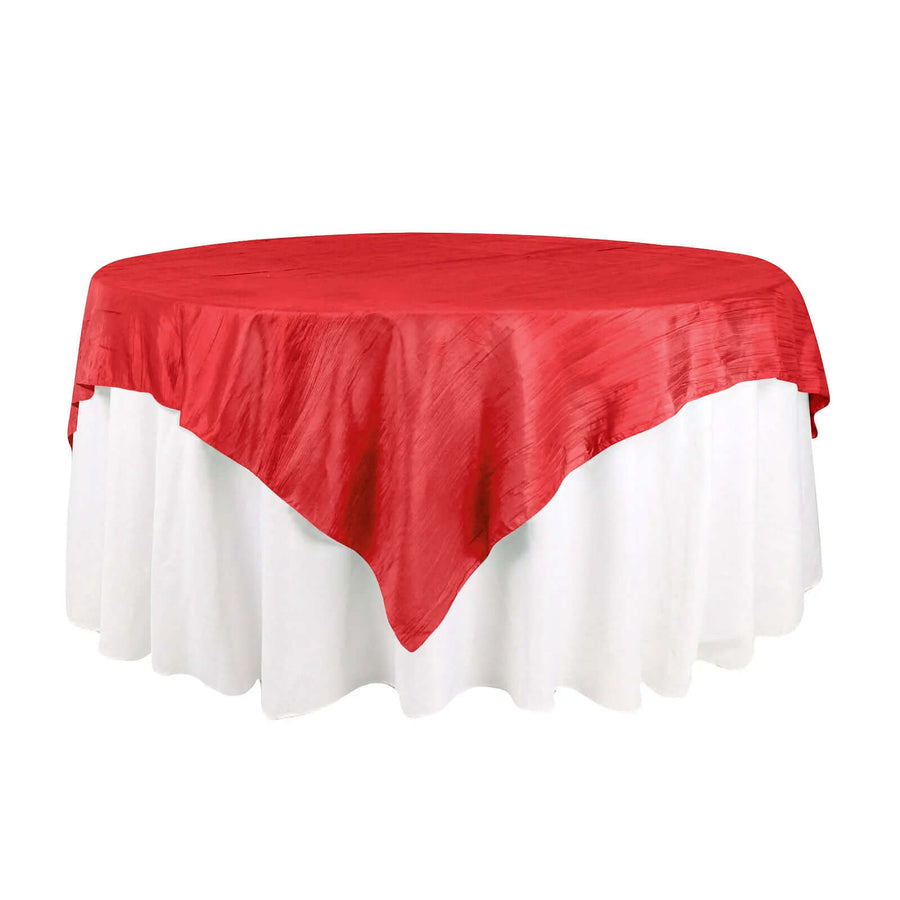 Red tablecloth draped over a round table with white skirt