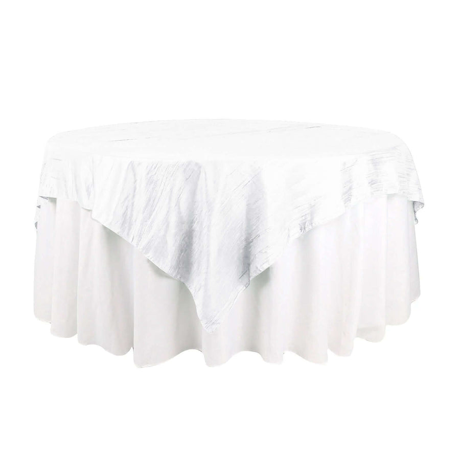 Round white table with a textured tablecloth on a plain background