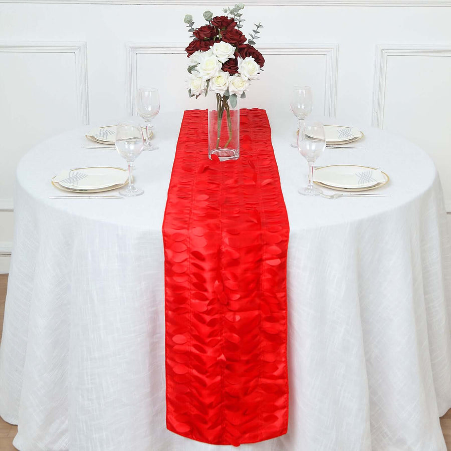 Red table runner on a white table with decorative flowers and dinnerware.