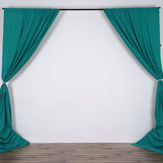 Teal fabric curtains draped on a black rod against a plain wall background.