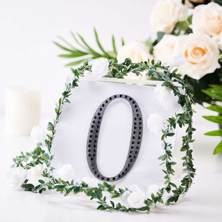 Decorative table number 0 surrounded by greenery and white roses