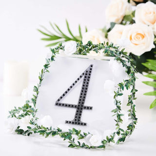 Elegant table number 4 adorned with greenery and white roses.