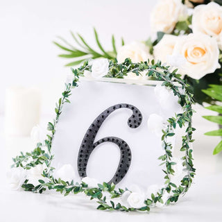 Table number six with floral decoration on a clear base.