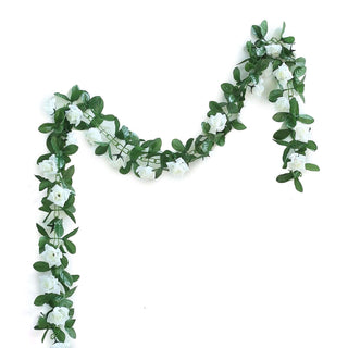 Artificial flower garland with white blooms and green leaves on a white background