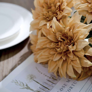 Dahlia flowers in warm tones on a decorative table setting.