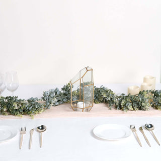 Gold geometric candle holder on a table with greenery and white plates