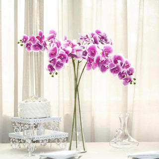Pink orchid arrangement in a clear vase on a table with elegant decor.
