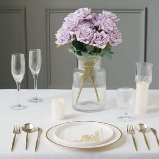 Elegant table setting with faux purple roses, glassware, and gold-accented dinnerware.