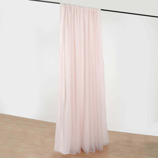 Pink sheer curtain draped on a rod against a plain background.