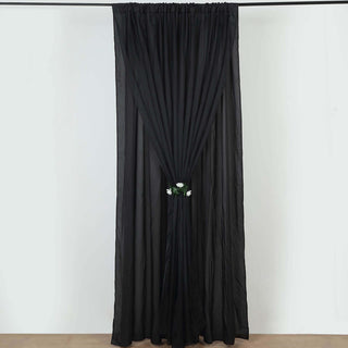 Black sheer curtain with floral tieback, elegantly draped.