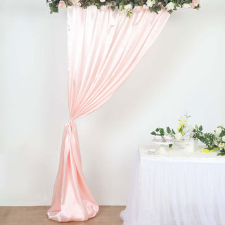 Pink satin backdrop with floral accents for events and photo shoots.