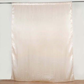 Beige silk curtain hanging from a rod against a plain backdrop