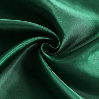 Green satin fabric swirl, showcasing smooth texture and rich color.