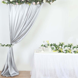 Elegant silver drapery with floral arrangement for event decor.