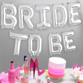 Silver "BRIDE TO BE" balloon banner with party decorations and cake.