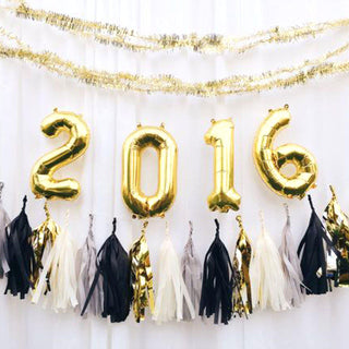 Gold and black 2016 balloons with tassels on a white backdrop.